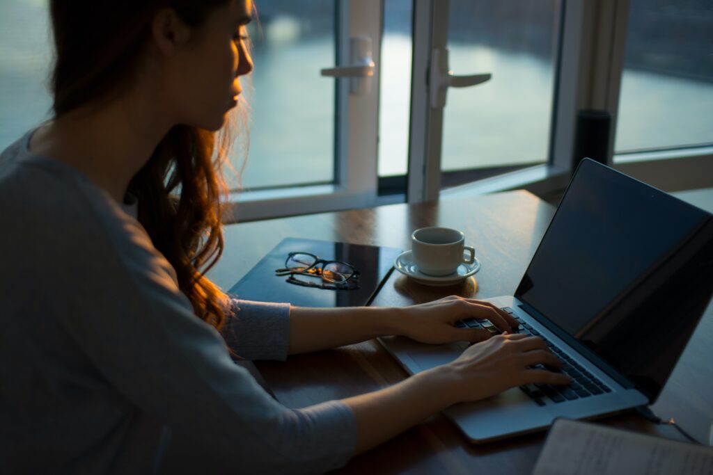 窓際でmac bookで作業する女性